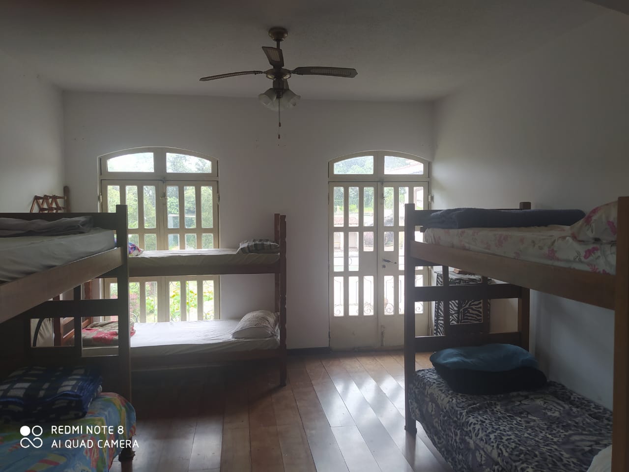 Dormitório amplo com camas e ventilação natural
